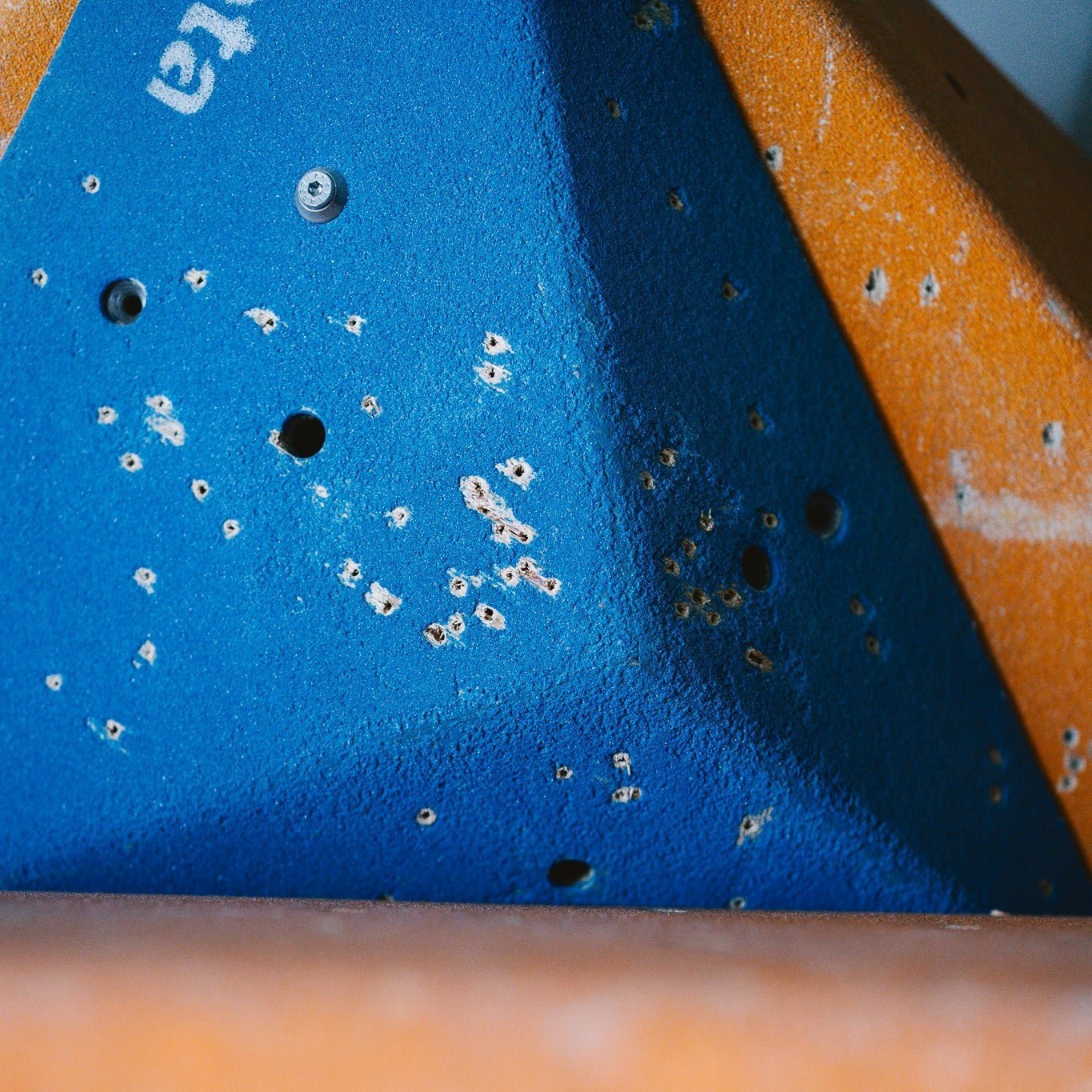 Ein blaues, dreieckiges Volumen mit Löchern in der Beschichtung das auf einem orangenen Volumen liegt.